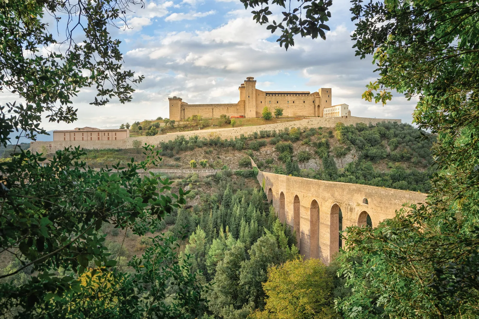 La Rocca Albornoziana di Spoleto sulla collina, con il Ponte delle Torri e i boschi in primo piano