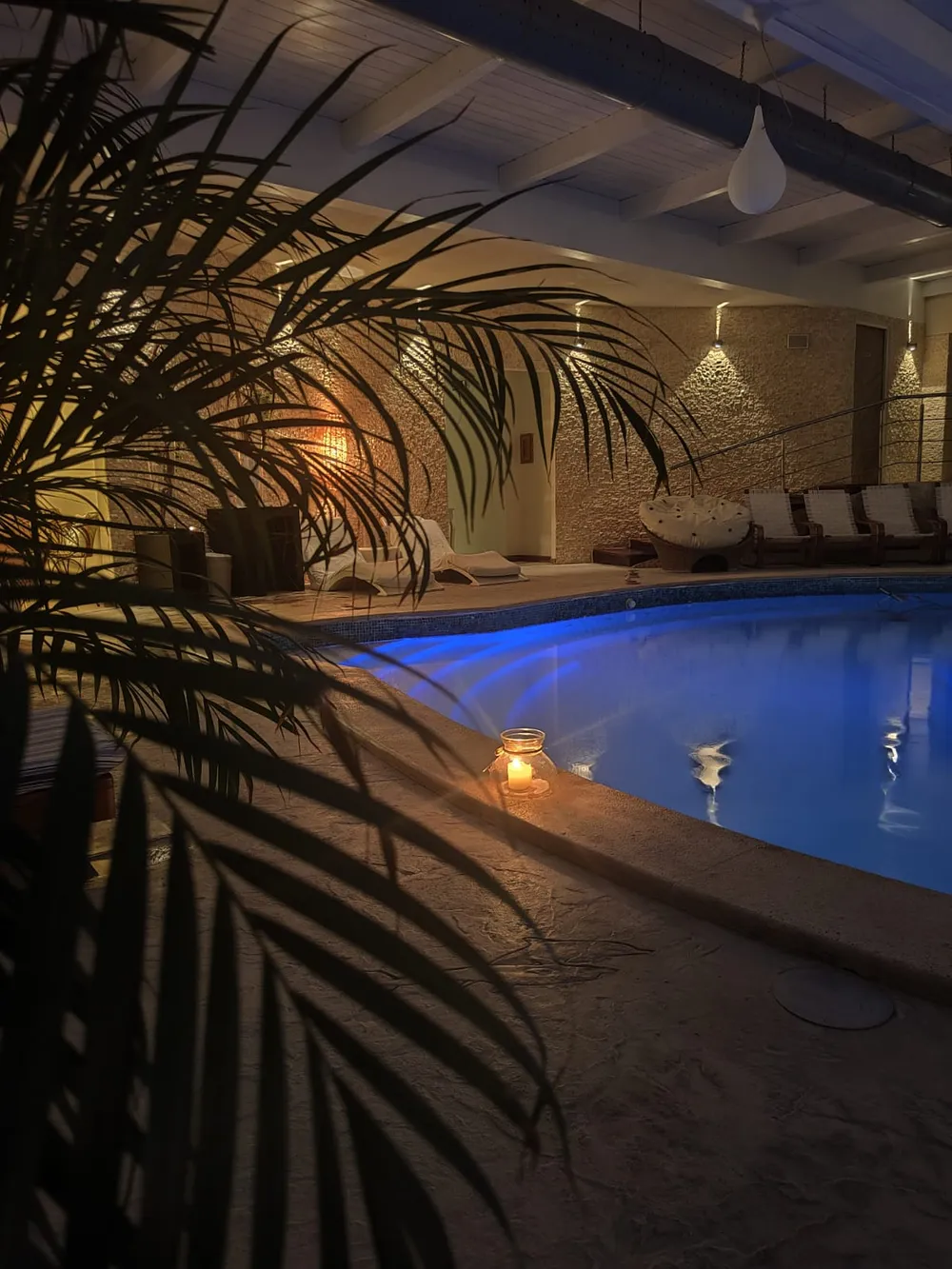 Piscina interna illuminata di blu la sera, con una lanterna accesa sul bordo